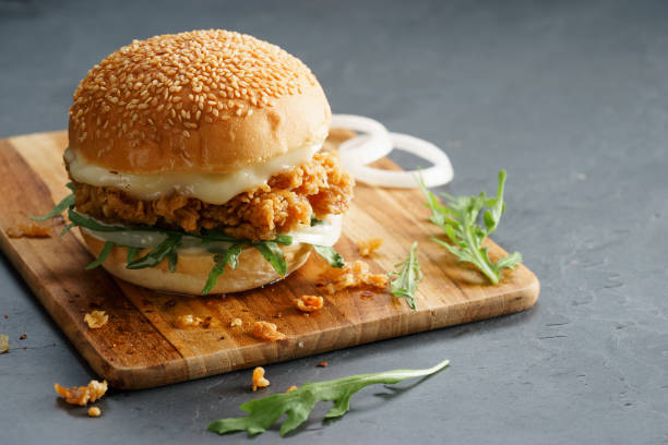 fried chicken burger Tasty fired chicken with arugula and mayonnaise sauce served on wooden board Chicken Burger stock pictures, royalty-free photos & images