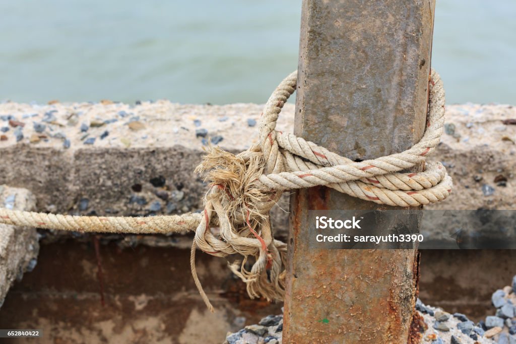 Old Fishing Boat Rope With A Tied Knot Around The Old Concrete