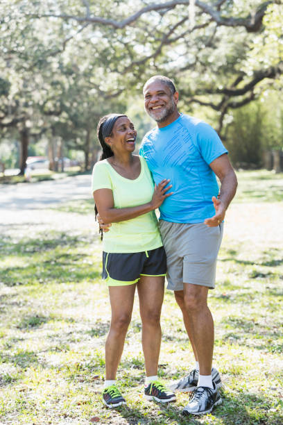 coppia afro-americana senior in piedi insieme nel parco - senior adult senior couple exercising african ethnicity foto e immagini stock