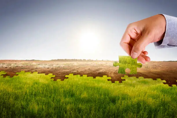 Businessman hand assemble puzzle to build new world with fresh environment. Climate change concept.