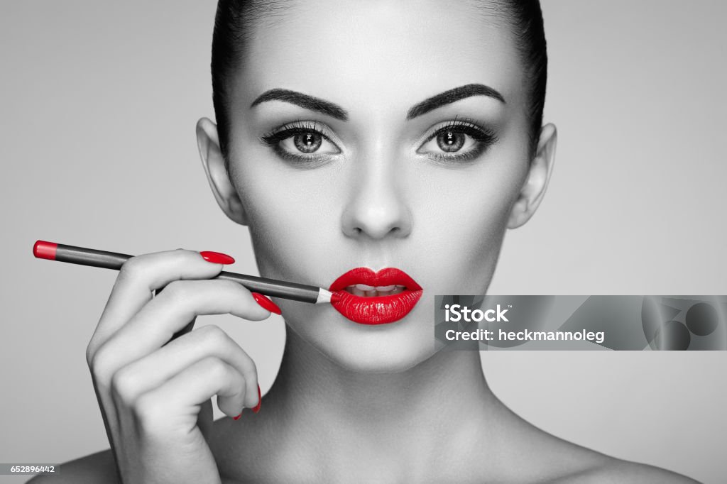 Black and white photo of woman painting lipstick Black and white photo of woman painting lipstick. Beautiful woman face. Makeup detail. Beauty girl with perfect skin. Red lips and nails manicure Black And White Stock Photo