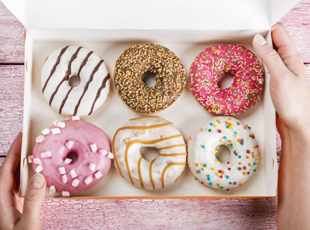 istock Female hands open a box of baked donuts 652904034