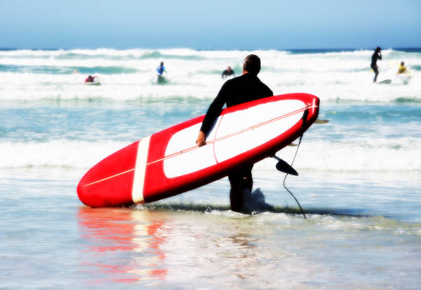 istock Surfer wades into the sea with board under arm 652908900