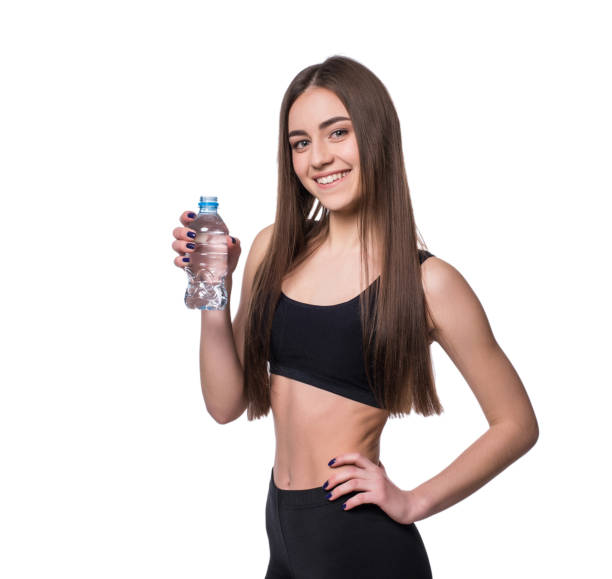 modèle positif femme fitness après entraînement tenant une bouteille d’eau pure sur fond blanc. - aerobics beautiful bottle body photos et images de collection