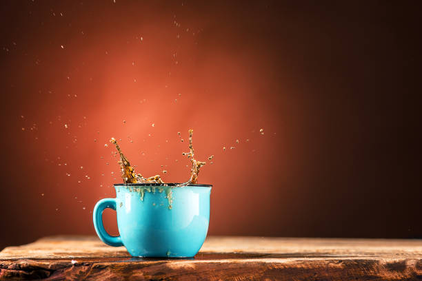 istock Brown splashes out drink from cup of tea on a brown background 652911870