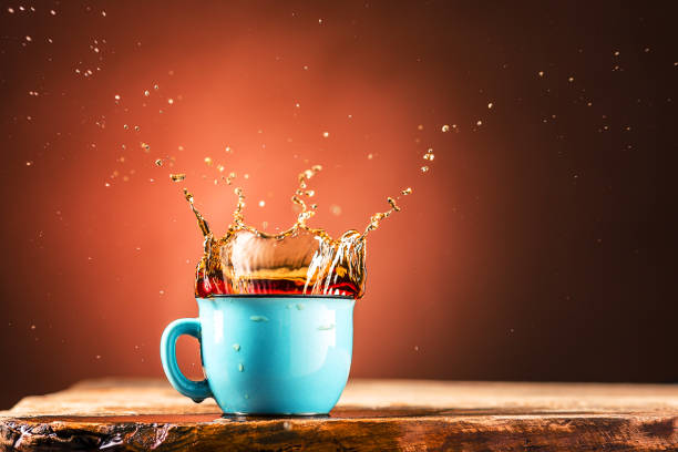 istock Brown splashes out drink from cup of tea on a brown background 652911922