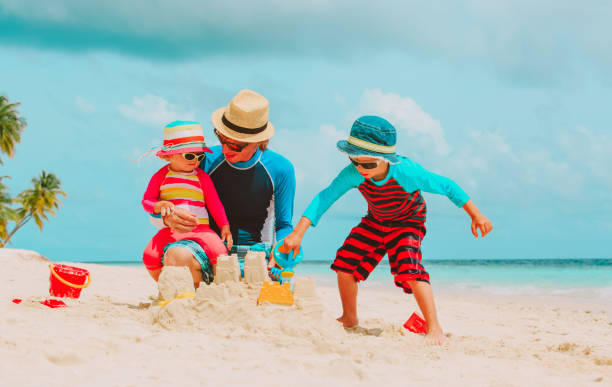 istock father with son and daughter building castle on beach 652915734