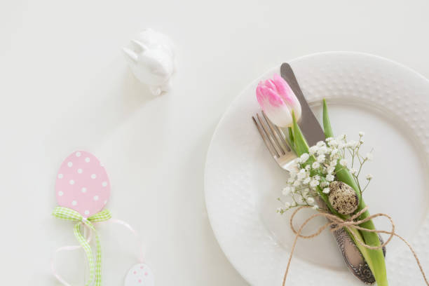 istock Easter table setting with pink ribbon and tulip on white background. Spring romantic dinner. Top view and copy space for your text. 652924200