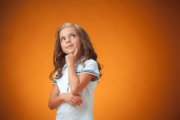 istock The cute thoughtful little girl on orange background 652936236