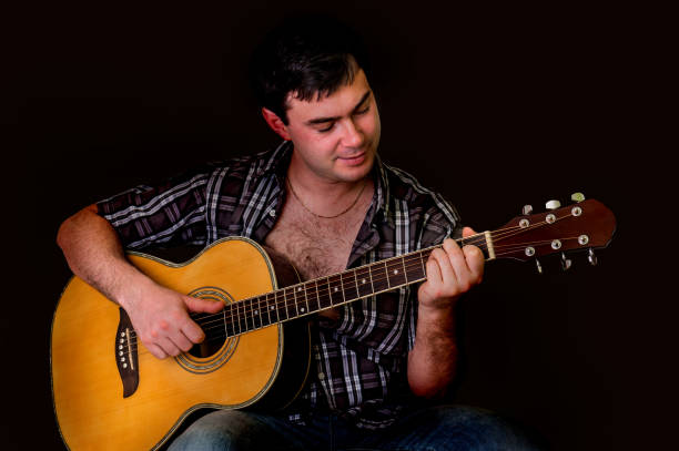 istock Young man playing acoustic guitar - isolated on black 652936328