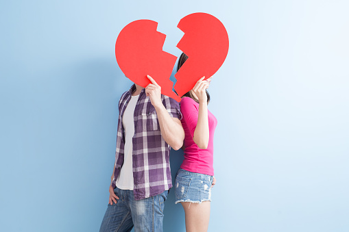 young couple take broken heart isolated on blue background