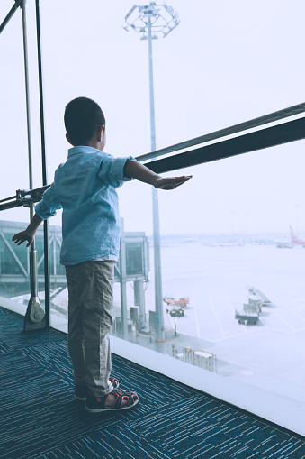 Boy outstretching arms in airport lounge