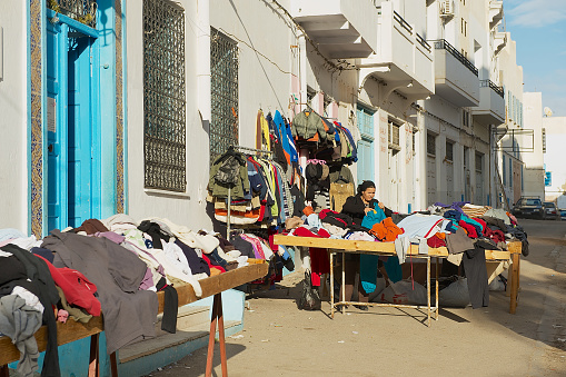 Sfax, Tunisia - November 30, 2011: Unidentified woman sells secons hand goods at the street in the medina of Sfax, Tunisia.