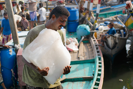 Negombo, Sri Lanka - March 7th 2023: Fisherman enjoying the morning sun on his boat outside the fish market in Negombo which is the largest in Sri Lanka and is a center for supplying fish to the capital Colombo and for export