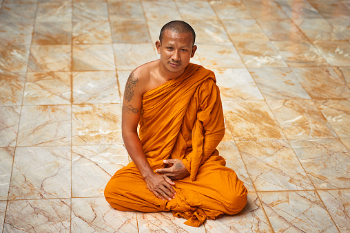 Portrait of a buddhist monk sitting on a monastary floor