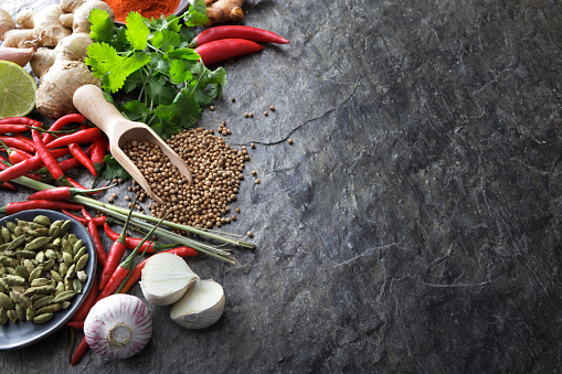 Seasoning (herbs and spices) on a wooden cutting board, on a modern gray kitchen table top, background ceramic texture for vegan or vegetarian food preparation, top view with a free space for copy