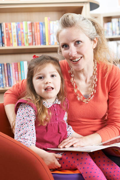 istock Mother And Daughter Reading Book In Library 653005118