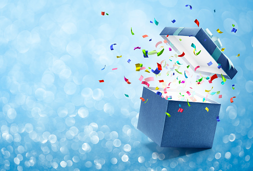 Confetti popping out from blue gift box - bokeh background