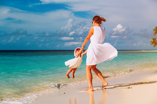 mother and cute daugher playing on tropical beach