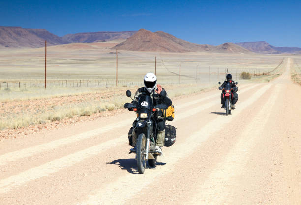 istock Two motorbikes driving fast on long straight desert road. 653014458