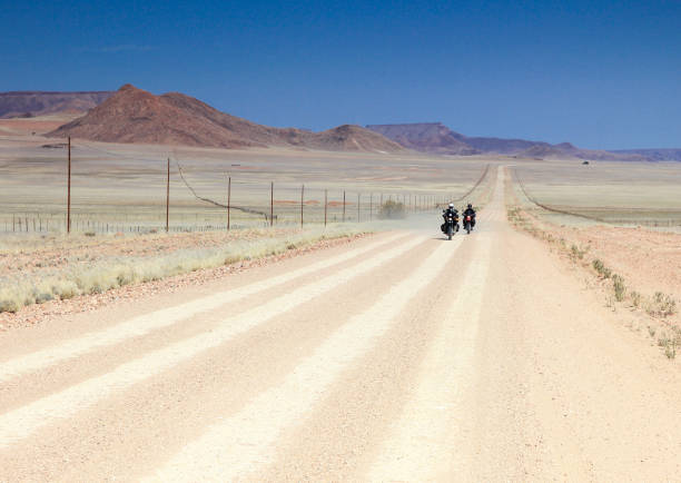 istock Two motorbikes driving fast on long straight desert road. 653014674