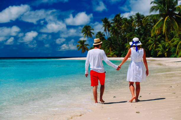 istock happy loving couple walking on beach 653014770