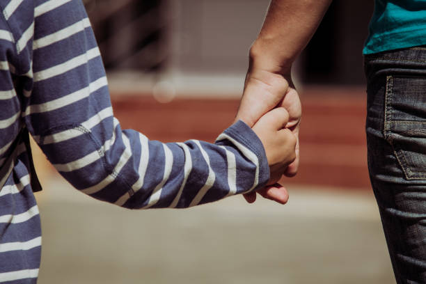 istock Mother holding hand of little son with backpack 653017862