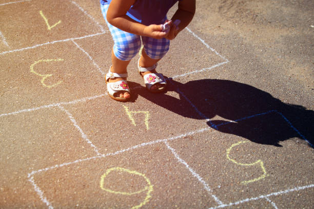 niña jugando hopscotch en el patio de recreo - little girls sidewalk child chalk fotografías e imágenes de stock