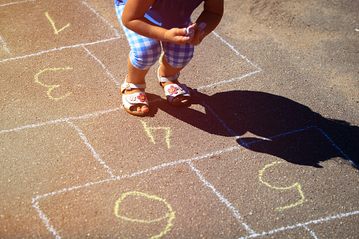 little girl playing hopscotch on playground outdoors