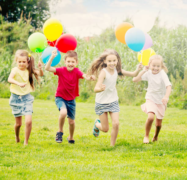 istock Four glad kids running on green lawn 653018304