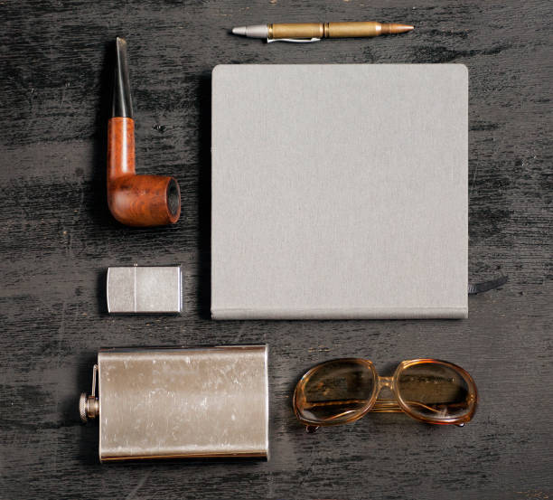 Gentlemanly set: metal flask for whiskey, Zippo lighter, sun glasses, traveler notebook, pen and smoking pipe.