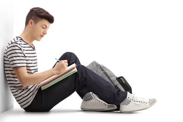 Photo of Teen student writing in a notebook