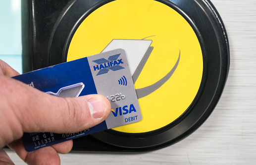 London, UK - Using a Contactless Visa Debit card, issued by Halifax Bank, to pay for a journey at the entry barrier of a London Underground station.