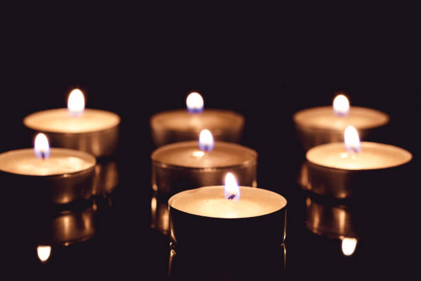 istock Group of tea candles on a black background. Selective focus 653065846