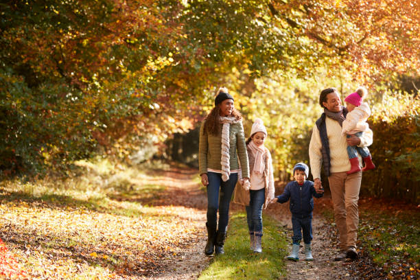 vista frontal de la familia disfrutando de paseo de otoño en el campo - couple mature adult action walking fotografías e imágenes de stock