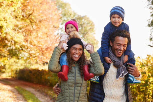 istock Autumn Walk With Parents Carrying Children On Shoulders 653069536
