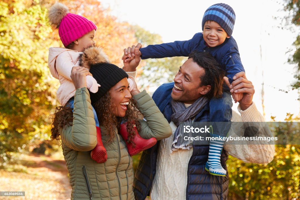 Autumn Walk With Parents Carrying Children On Shoulders Family Stock Photo