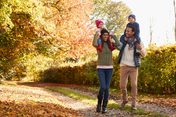 marche d’automne avec des parents portant des enfants sur des épaules - baby carrier photos photos et images de collection