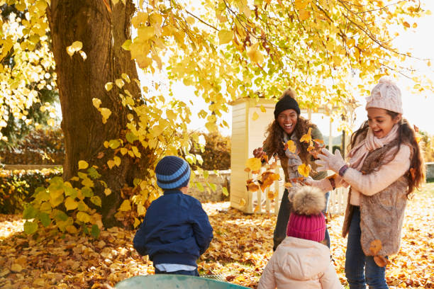 kinder helfen mutter herbstlaub im garten sammeln - family african ethnicity black african descent stock-fotos und bilder