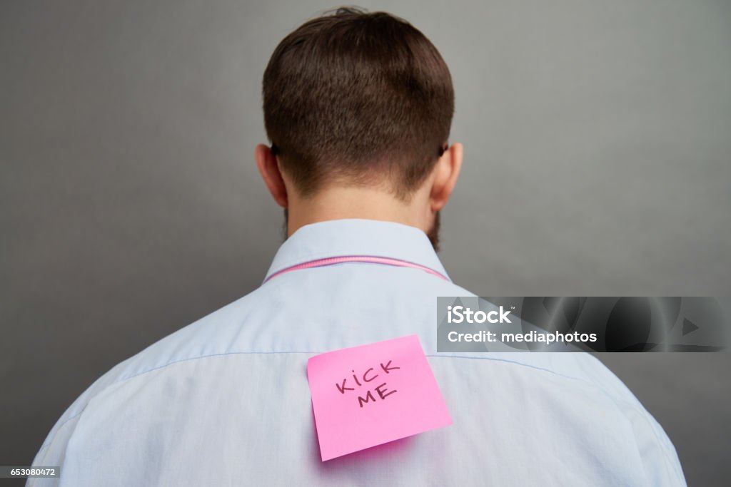 Pranked man Rear view of man with note on his back April Fools Day Stock Photo