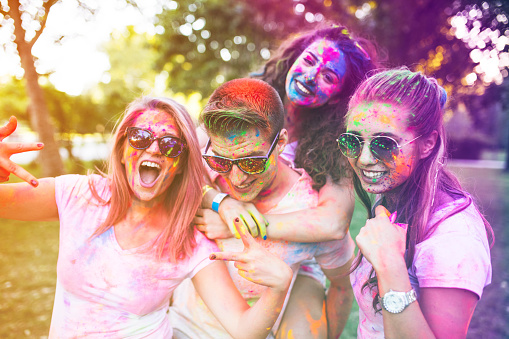 Group of colorful friends playing with color dust at the countryside