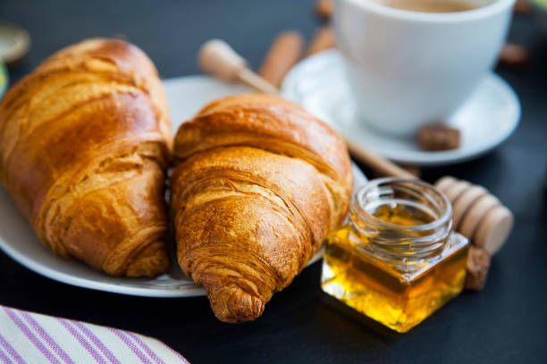 istock Fresh croissants with honey jar and coffee, breakfast setting, selective focus 653081258