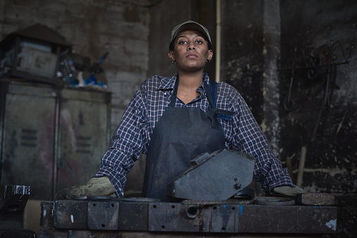 Unflappable female blacksmith with dirt on face working in smithy
