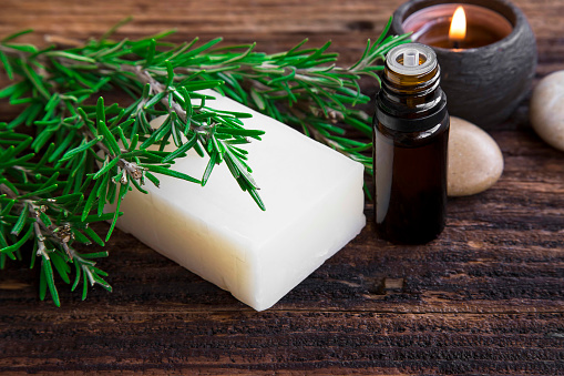 Rosemary soap and essential oil aromatherapy with candle on wooden background