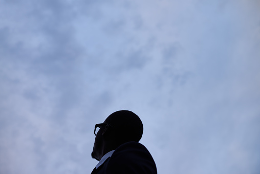 African businessman in eyewear looking at dark sky
