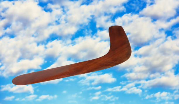 wooden australian boomerang in flight against of pure white clouds. - boomerang imagens e fotografias de stock