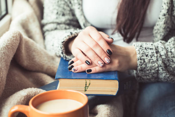 istock Young woman reading book, close-up, on home interior 653105058