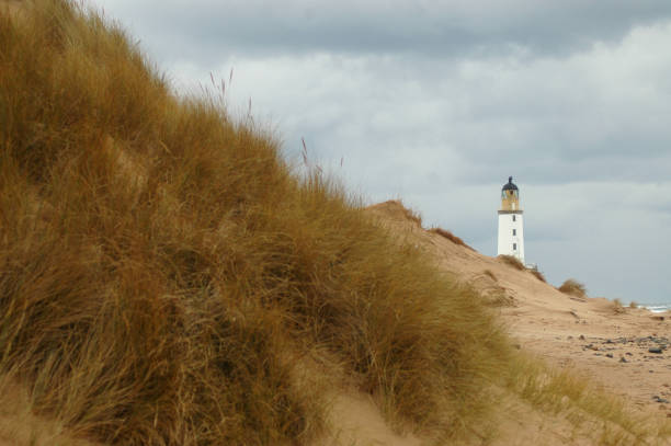 Lighthouse Behind Sand Dunes stock photo