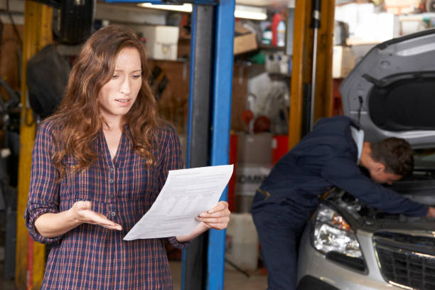 cliente femenino sorprendido mirando la factura del garaje - customer auto repair shop car mechanic fotografías e imágenes de stock