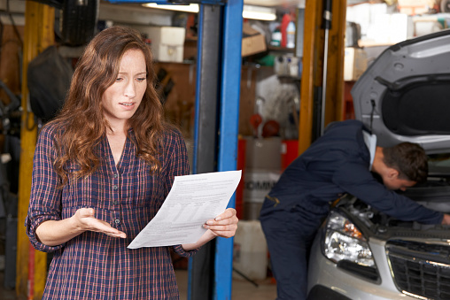 Shocked Female Customer Looking At Garage Bill
